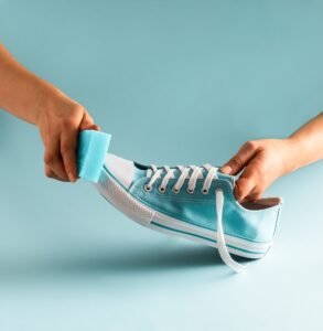 Women's hands with a blue snickers and sponge. Shoe cleaning and care concept.